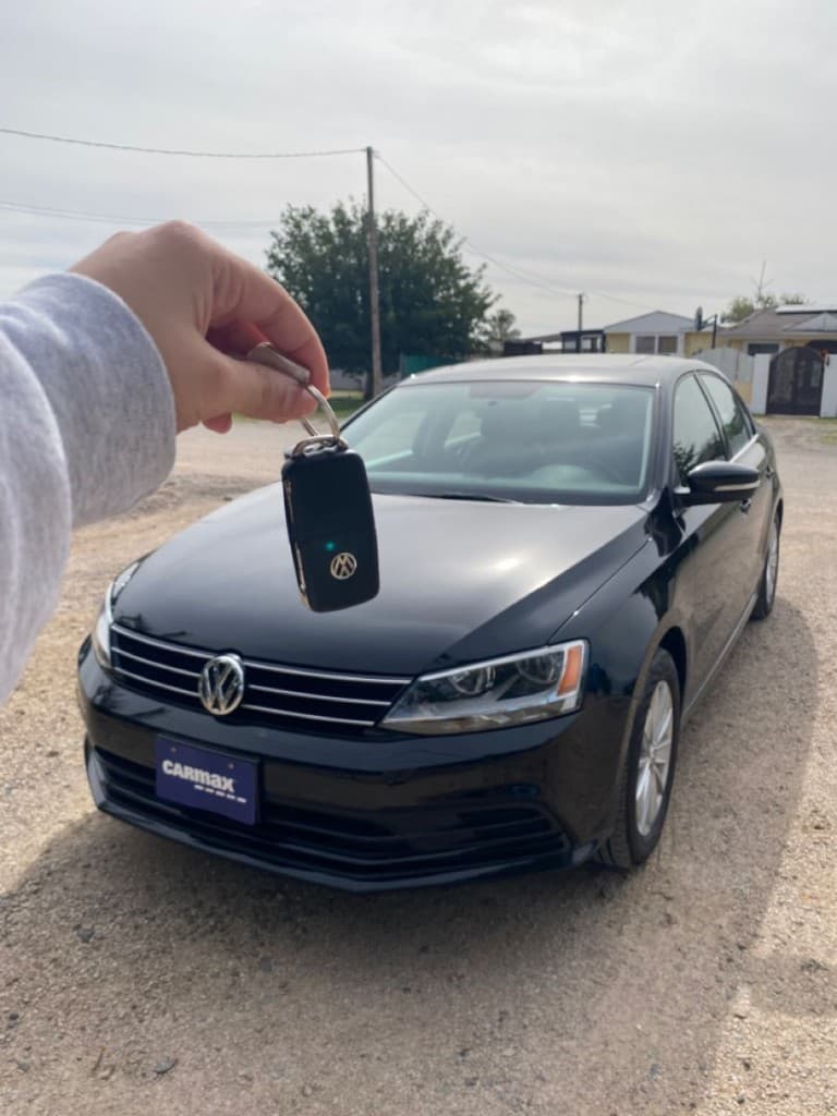 Volkswagen Jetta key fob held in front of a black VW sedan